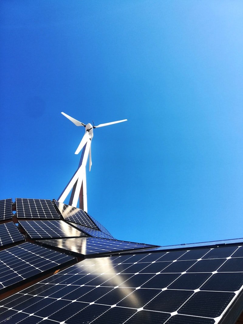 Painéis solares e turbina eólica sob céu azul