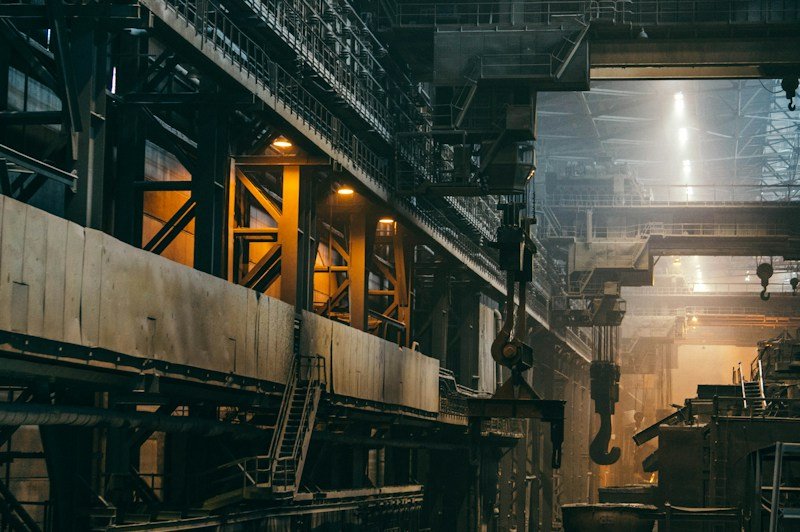 Interior de planta industrial pesada com estrutura metálica e guindaste