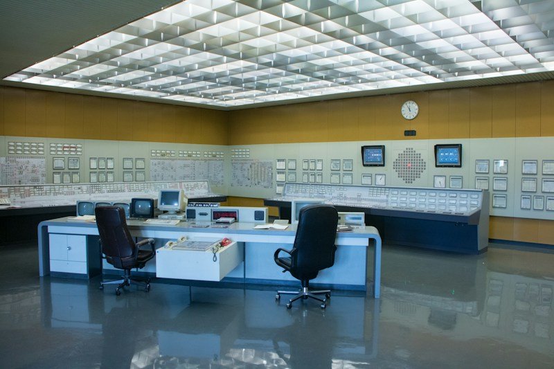 Sala de controle industrial com múltiplos painéis e monitores